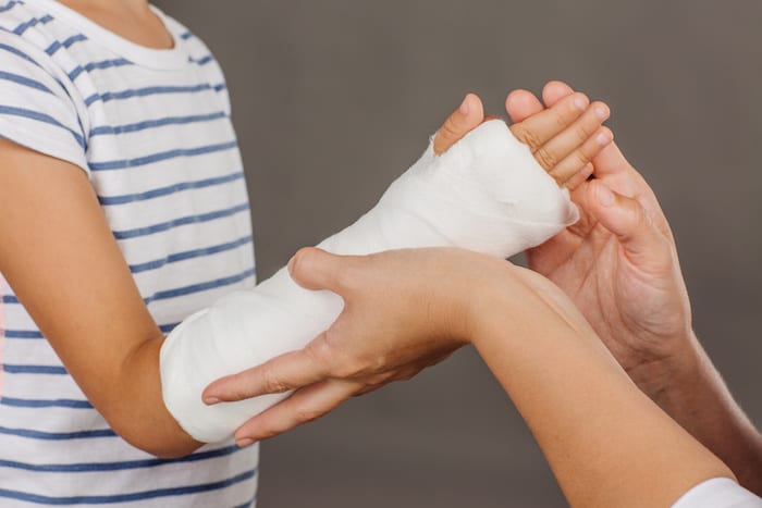 doctor inspecting hand of little patient. medicine, health care and people concept; Blog: What to do when your child breaks a bone