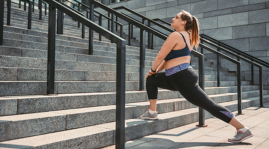 Stretching after great workout. Happy plus size woman in sport clothes doing stretching exercises on the stairs outdoors. Healthy life. Sport concept. Weight losing; blog: Ways to Avoid Workout Injuries